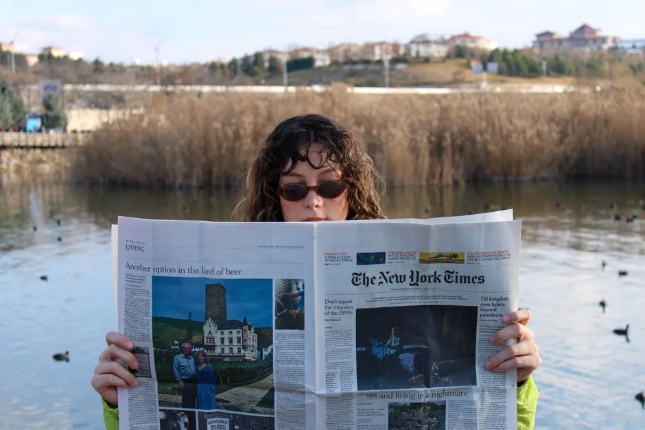 Newspaper front pages from several decades spread across a reading table